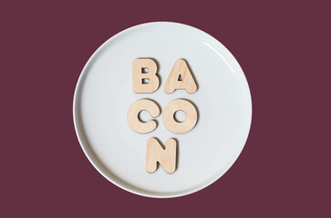 The word Bacon made of wooden letters on a round white plate