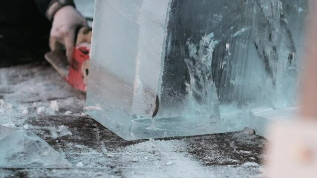 Slomo shot of chainsaw cutting through large block of ice. Close up, static