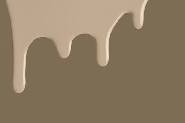 Beige liquid drops of paint color flow down on brown background. Abstract umber backdrop with sand fluid drip