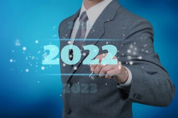 Businessman in a suit chooses 2022 on a background. new year start ideas