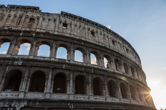 The sun sets on the Colosseum in Rome, Italy, the largest ancient amphitheatre ever built, during a cloudless summer day.