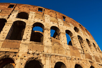 Obraz premium The sun sets on the Colosseum in Rome, Italy, the largest ancient amphitheatre ever built, during a cloudless summer day.