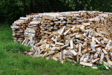 Birch firewood in a woodpile on the grass.