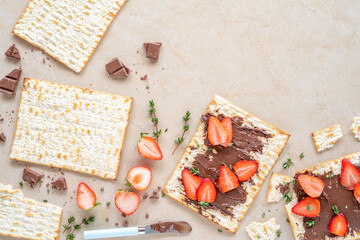 Matzah bread with fresh strawberries and chocolate cream on marble background. Food ideas for Jewish holiday Pesach.