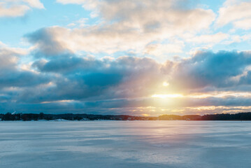 Beautiful winter sunset over the frozen lake. Ice with sunset reflections in the foreground cloudy sky winter.