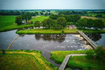 Drone view of the river Vecht, green grass, trees, beautiful blue sky and cycle path through the Vecht valley. Bridge and weir in the river. Dalfsen Netherlands