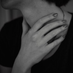 Black and white deep photo of a young girl's hands at the neck with short dark hair