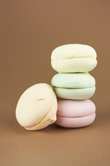 Colorful marshmallows looks like french macarons on pastel cream background, close up, colorful almond cookies, pastel colors