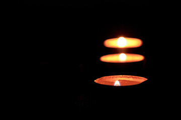Three candles in the dark with soft focus and bokeh.