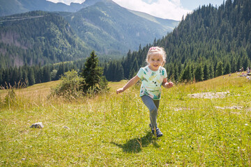 Fototapeta na wymiar Little girl is relaxing on meadow . Tatra mountains in background. Summer vacation