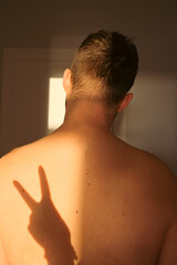 Naklejka premium strong men's naked back with peace sign shadow. morning wake up, pain in the neck