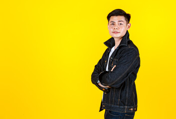 Plakat Portrait studio shot Asian young handsome male hipster model wearing casual street denim jacket jeans standing look at camera posing on yellow background.