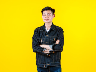 Portrait studio shot Asian young handsome male hipster model wearing casual street denim jacket jeans standing look at camera posing on yellow background.