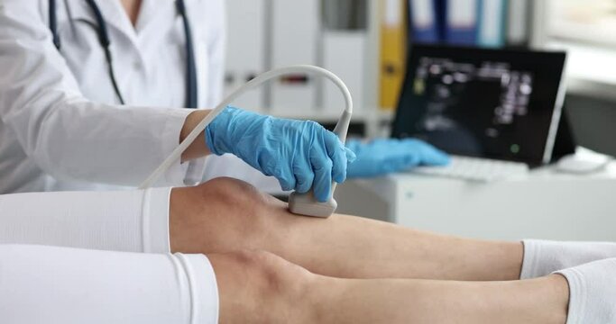Doctor in rubber gloves scans patient leg with ultrasound machine