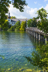 Fototapeta premium background view of a wooden bridge and Orth castle on an island in the middle of the Traunsee lake, Gmunden, Austria, Europe