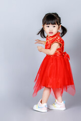 Studio full body shot of little cute innocent kindergarten preschooler girl daughter in traditional oriental red qipao cheongsam dress looking aside celebrate Chinese new year on gray background