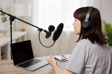 portrait of young woman recording podcast at home