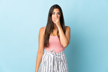 Young brazilian woman isolated on blue background surprised and shocked while looking right