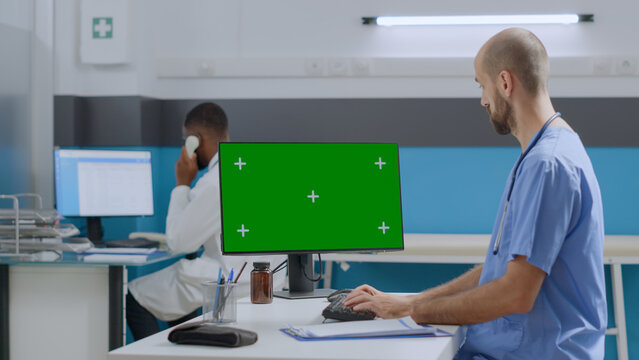 Therapist man nurse typing disease expertise after analyzing medical documents working at healthcare treatment in hospital office. Mock up green screen chroma key computer with isolated display