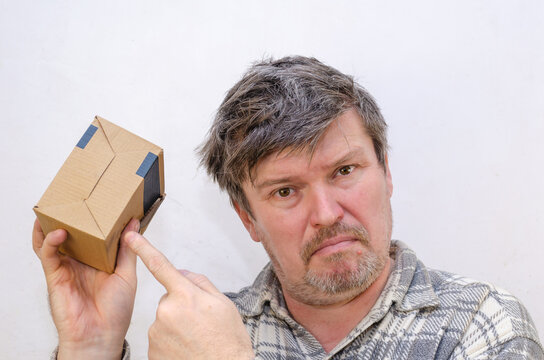 An Adult Male Is Holding A Small Cardboard Box.