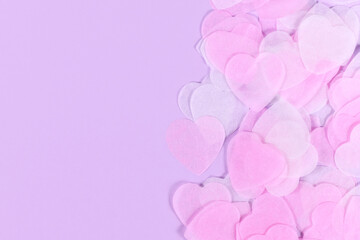 Pastel pink and white heart shaped paper confetti on violet background with copy space