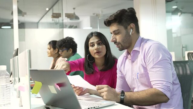 Indian Female manager insurer consulting male customer with laptop at meeting young Asian woman or mentor showing online presentation of deal benefits talking convincing client teaching intern office.