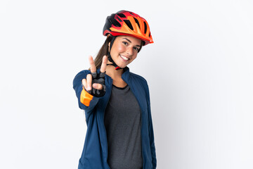 Young cyclist brazilian girl isolated on white  background smiling and showing victory sign