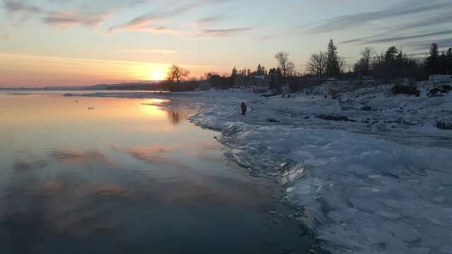 Water reflecting sunset light, ice formations on the shore, winter landscape Lake Superior