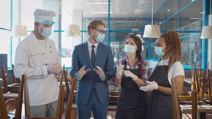 Manager in safety mask having briefing with restaurant team before opening. Realtime