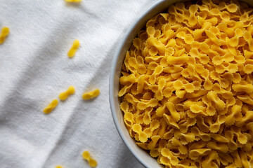 Healthy Dry Farfalline Pasta in a Bowl, top view. Flat lay, overhead, from above. Copy space.