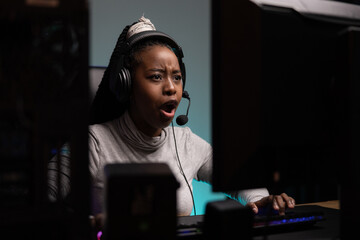 Shot from behind computer monitor of nervous pro gamer. Woman makes disgusted face talks to team...