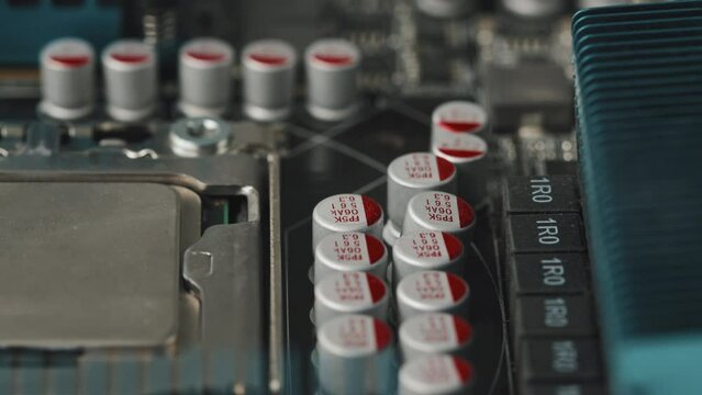 Macro tracking shot of electrolytic chip capacitors on circuit board with electronic components