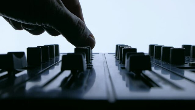 Silhouette of Professional sound engineer or music DJ balancing volume of audio inputs of digital audio mixer. Hand pushing a fader of a mixing console. 
