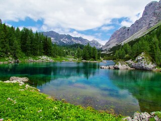 Beutiful colorful lake at Triglav lakes valley in Triglav national park and Julian alps in Gorenjska region of Sloven with mountains in the back and a mountain hut at the far side of the lake