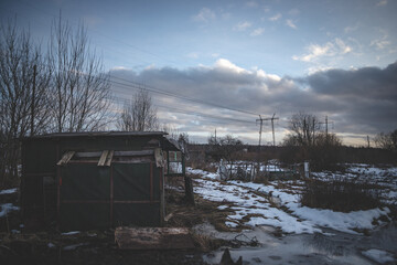 abandoned garden houses in neglected area, high voltage power lines, blue sky, fluffy clouds	