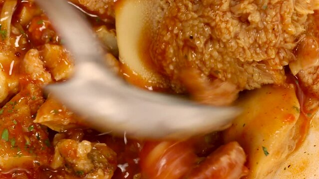 Macro shot of spoon mixing spanish tripe dish callos. Pork meat traditional spanish gastronomy. Tripe Madrid style.