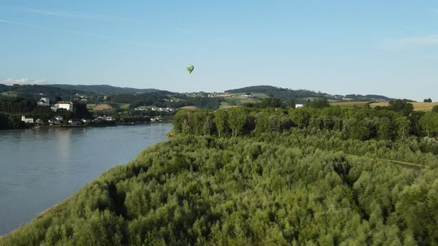 A hot air baloon climbing up above the countryside of upper austria.