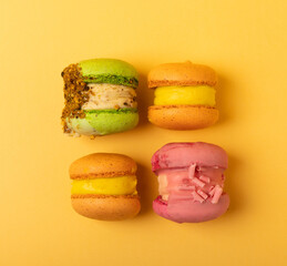 Delicious berry macaroons on a soft yellow-orange paper background. French meringue cookies macaron. Culinary and cooking concept. Copy space. top view.