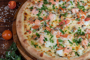 Pizza with bacon and cheese, herbs and cherry tomatoes. With mozzarella, shrimps and octopuses, mussels and other products on a wooden background.