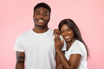 Confident couple standing and posing at pink studio background