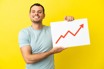 Brazilian man over isolated purple background holding a sign with a growing statistics arrow symbol