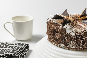 close up view on sweet cake with a cup of tea or coffee and kitchen towel on a light background