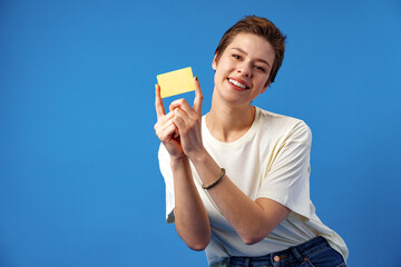 Image of young woman holding business card with copy space on blue background