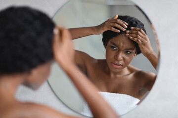 Upset african american woman checking her hair - obrazy, fototapety, plakaty