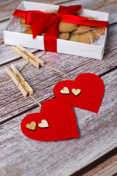 Valentines day gift with red ribbon, heart shaped cookies. Red hearts on wooden background. Vertical photo.