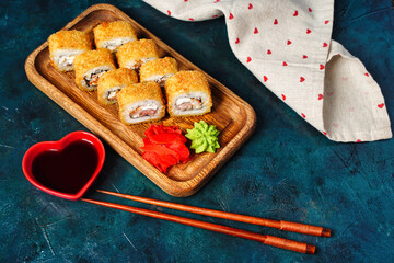 Fried tempura sushi rolls set on wooden plate on dark background. Japanese traditional fusion food style, restaurant menu background, degustation, buffet