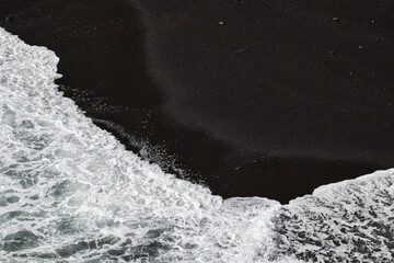 Spray washes over black lava sand