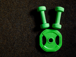 green heavy dumbbells and barbell metal weight disc in shape of Easter bunny on black background....