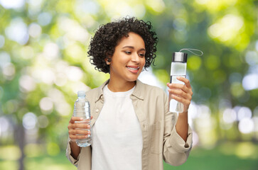eco living, zero waste and sustainability people concept - happy smiling woman with water in glass...