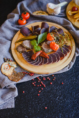 Wooden tray with sliced salami, basturma, cheese and other snacks